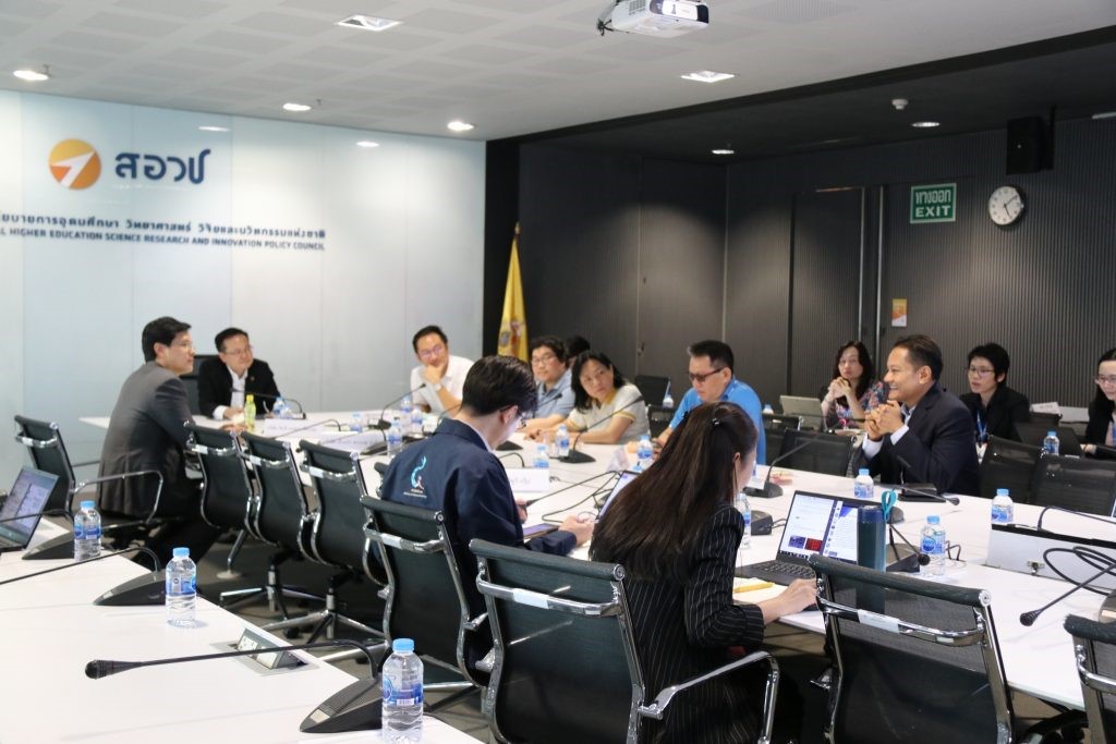 A group of people sitting at a desk in front of a computer  Description automatically generated