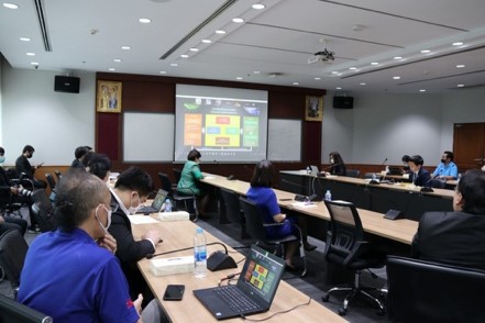 A group of people sitting at a desk in front of a computer screen Description automatically generated