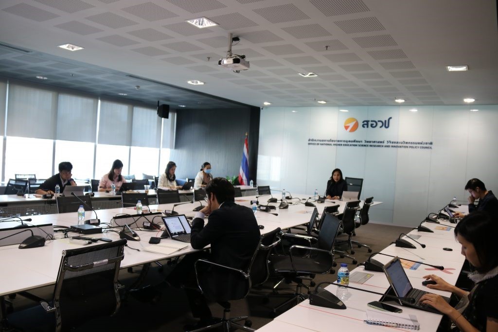 A group of people sitting at a desk with a computer in an office  Description automatically generated