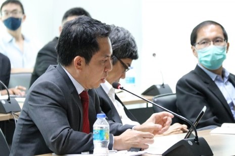 A group of people sitting at a desk looking at a computer Description automatically generated